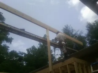 Carpenter setting a ridge beam over a new addition frame — Ice Dam Removal by Roofing Brothers in Gales Creek
