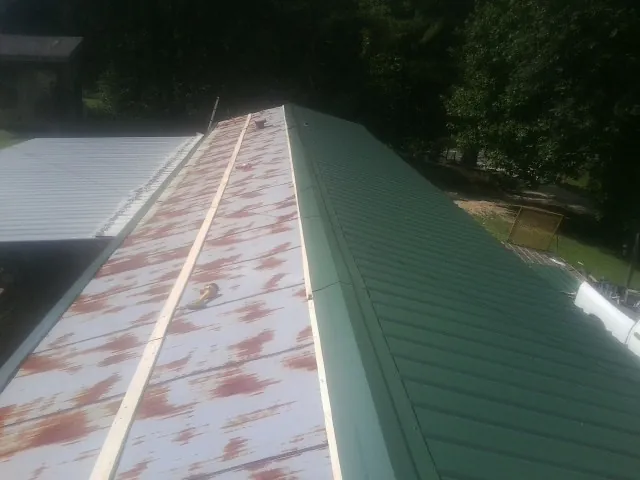 Old rusted panels beside newly installed green metal roofing — Wind Damage Roof Repair by Roofing Brothers in Gales Creek
