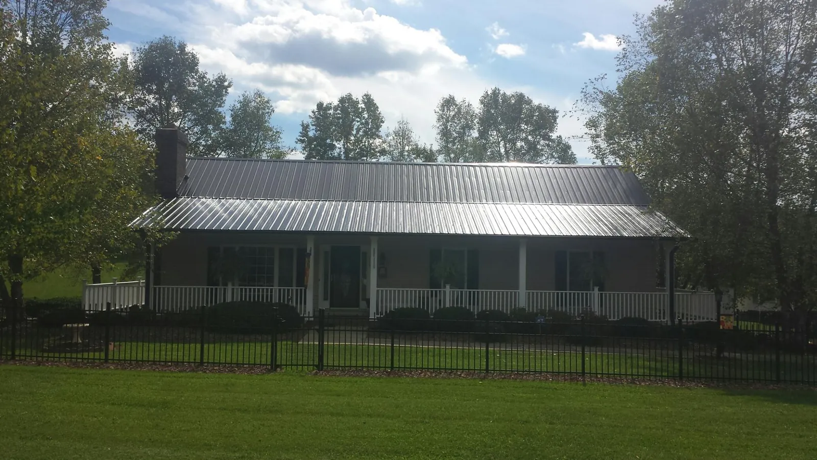 Gray metal roof on a brick ranch with a full width front porch — Gutter Guard Installation work by our crew in Gales Creek