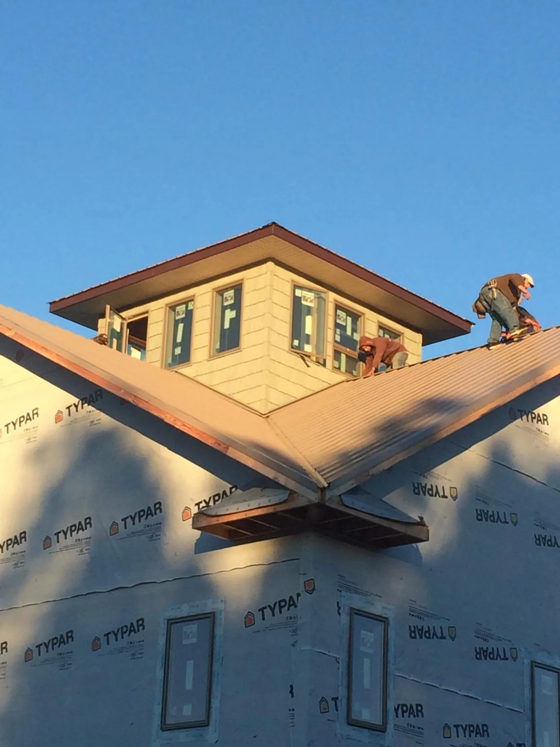 Roofers working around a rooftop cupola on a new metal roof at sunset — Roof Waterproofing in Gales Creek by Roofing Brothers